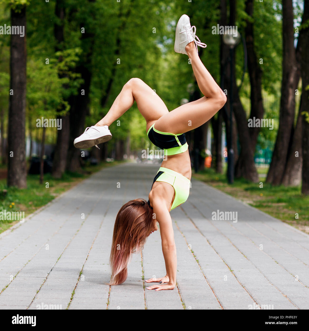 Young sporty woman stands on hand in the park. Stock Photo