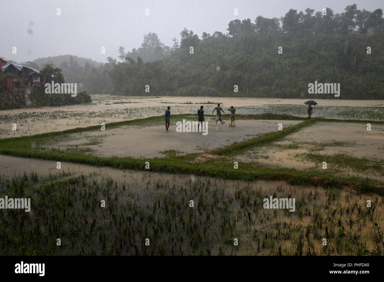 Rohingya men play soccer in a flooded field in Charkmakul, one of the camps sheltering over 800,000 Rohingya refugees, Cox's Bazar, Bangladesh, June 1 Stock Photo