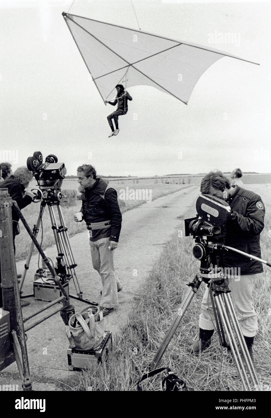 Film crew on location filming Tommy in 1974 with stand-in on hang glider Stock Photo
