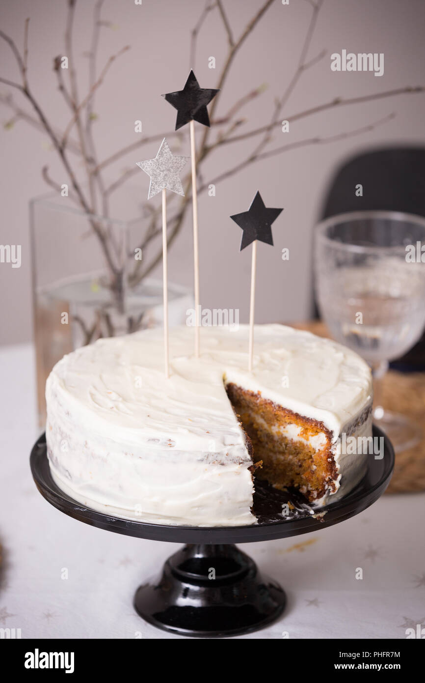 Close up of delicious homemade birthday white cake decorated with silver stars on the table. Baking at home for events. Cooking sweet cake for holiday Stock Photo