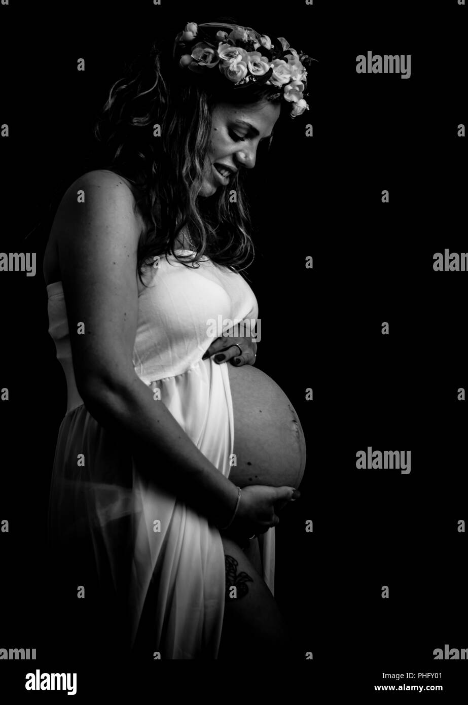 Monochrome - mother to be looking down and cradling her bump Stock Photo