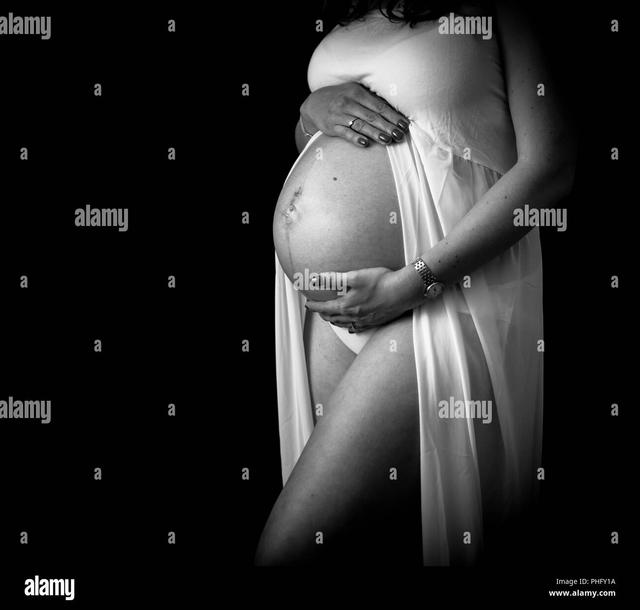 monochrome - mother to be 3/4 length shot cradling bump, pregnant belly, bump Stock Photo