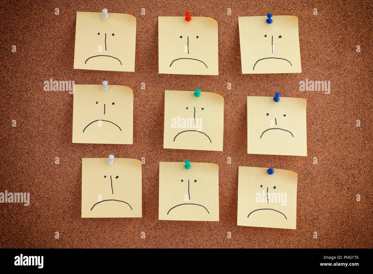 Post it notes with sad faces on bulletin board. Close up. Stock Photo