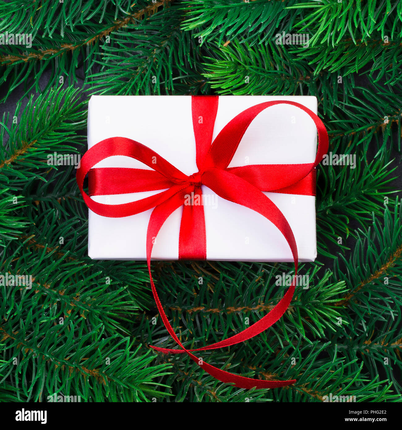 Christmas tree branch on a black background and gift box with a red ...