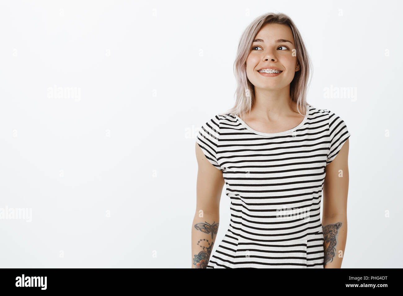 Waist-up shot of dreamy stylish woman with cool tattoos on arms ...