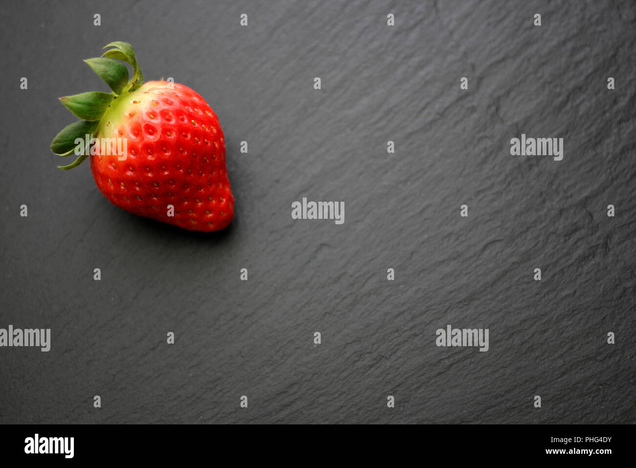 Single strawberry on slate plate Stock Photo