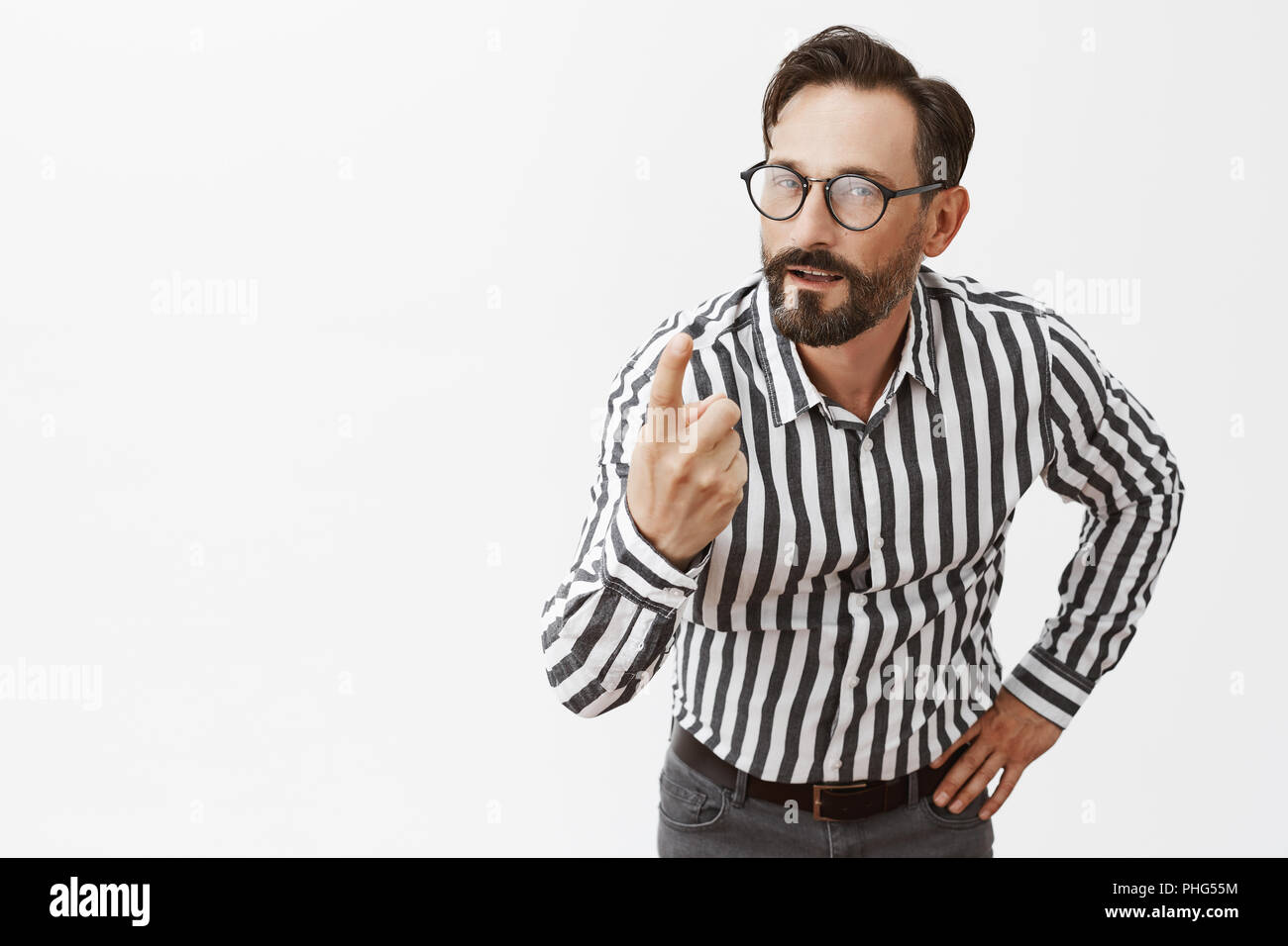 One more chance to proof your useful. Charming confident and bossy mature guy with beard and moustache, bending towards camera with raised index finger, holding hand on waist, giving directions Stock Photo