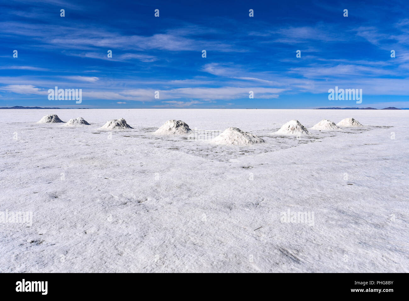 Piles of salt drying in the sun near the mining town of Colcani. Salar de Uyuni, the worlds largest salt flats, Bolivia Stock Photo