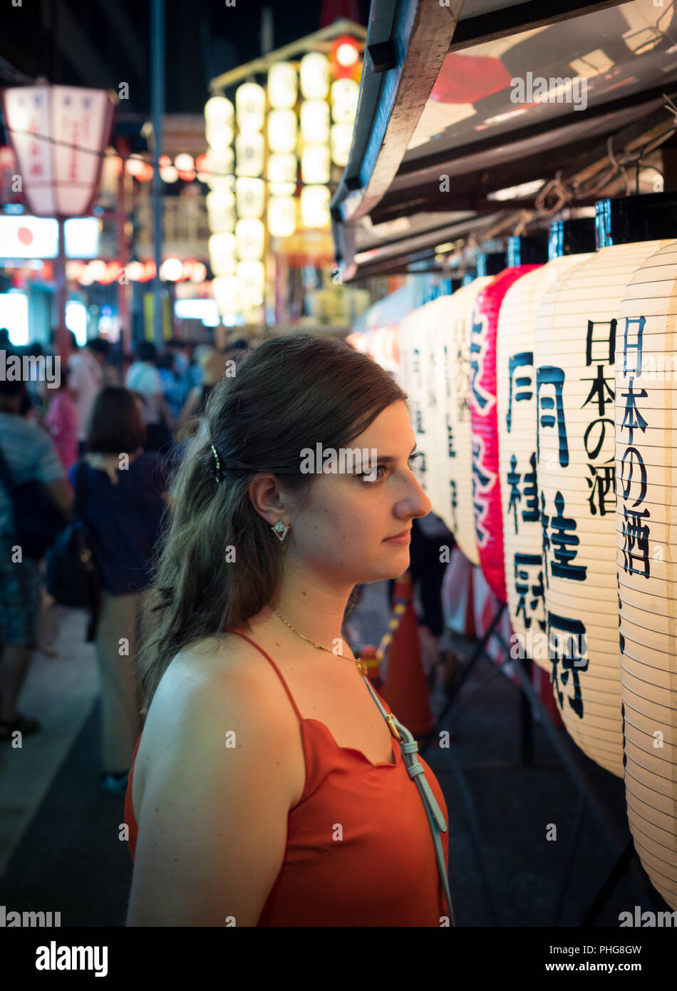 A tourist looks at illuminated lanterns on Shijo-dori (Shijo street) during the Yoiyama street party at the 2018 Gion Matsuri festival. Kyoto, Japan. Stock Photo