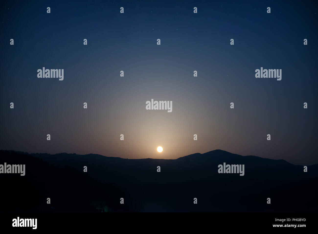 Moon rising on night sky Stock Photo