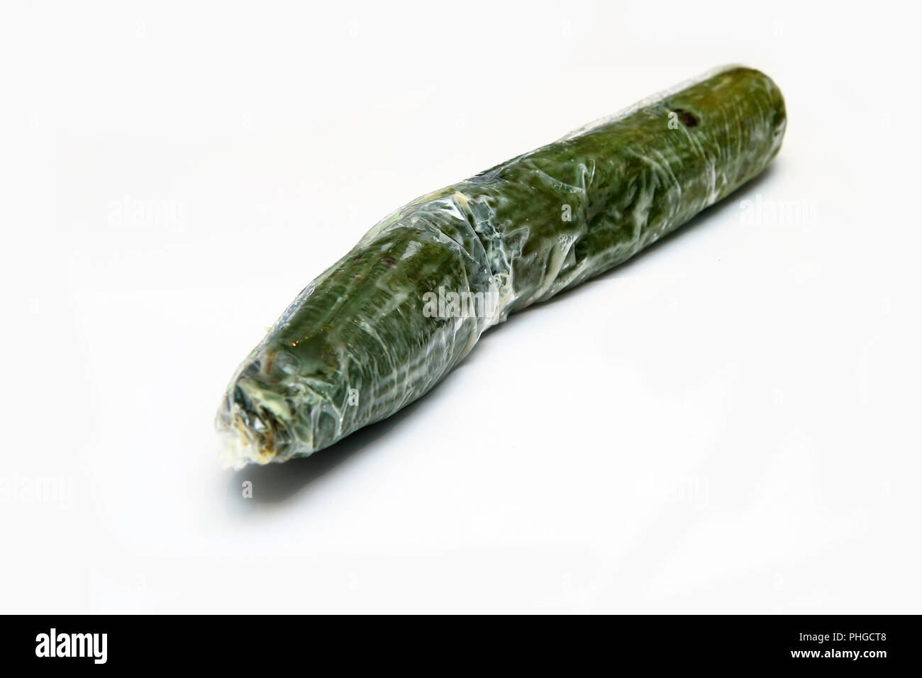 A picture of a rotten cucumber packed in the plastic foil. The foil is useless, it only damages the vegetable and it only goes mouldy. Isolated Stock Photo