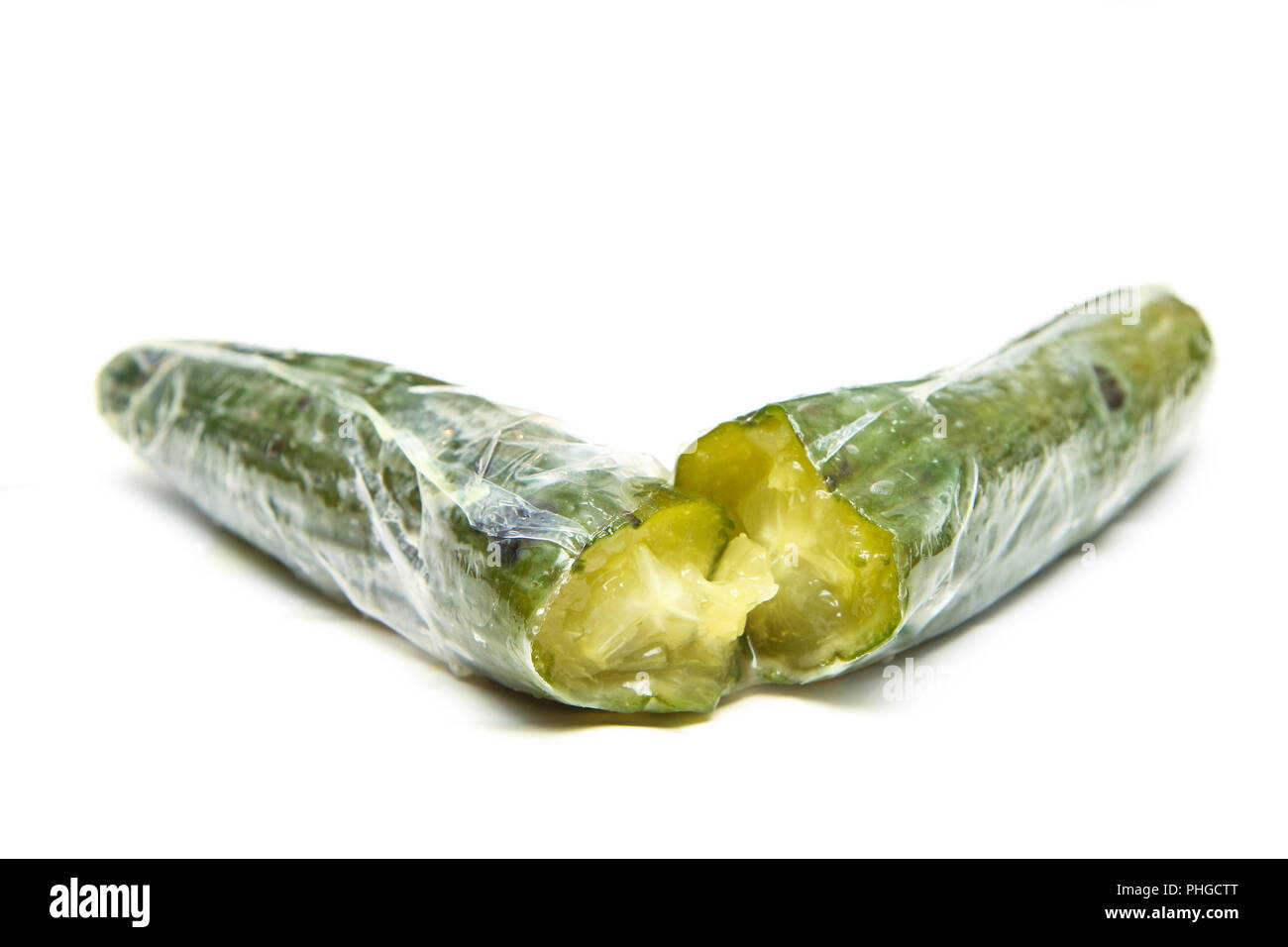 A picture of a rotten cucumber packed in the plastic foil. The foil is useless, it only damages the vegetable and it only goes mouldy. Isolated on a w Stock Photo