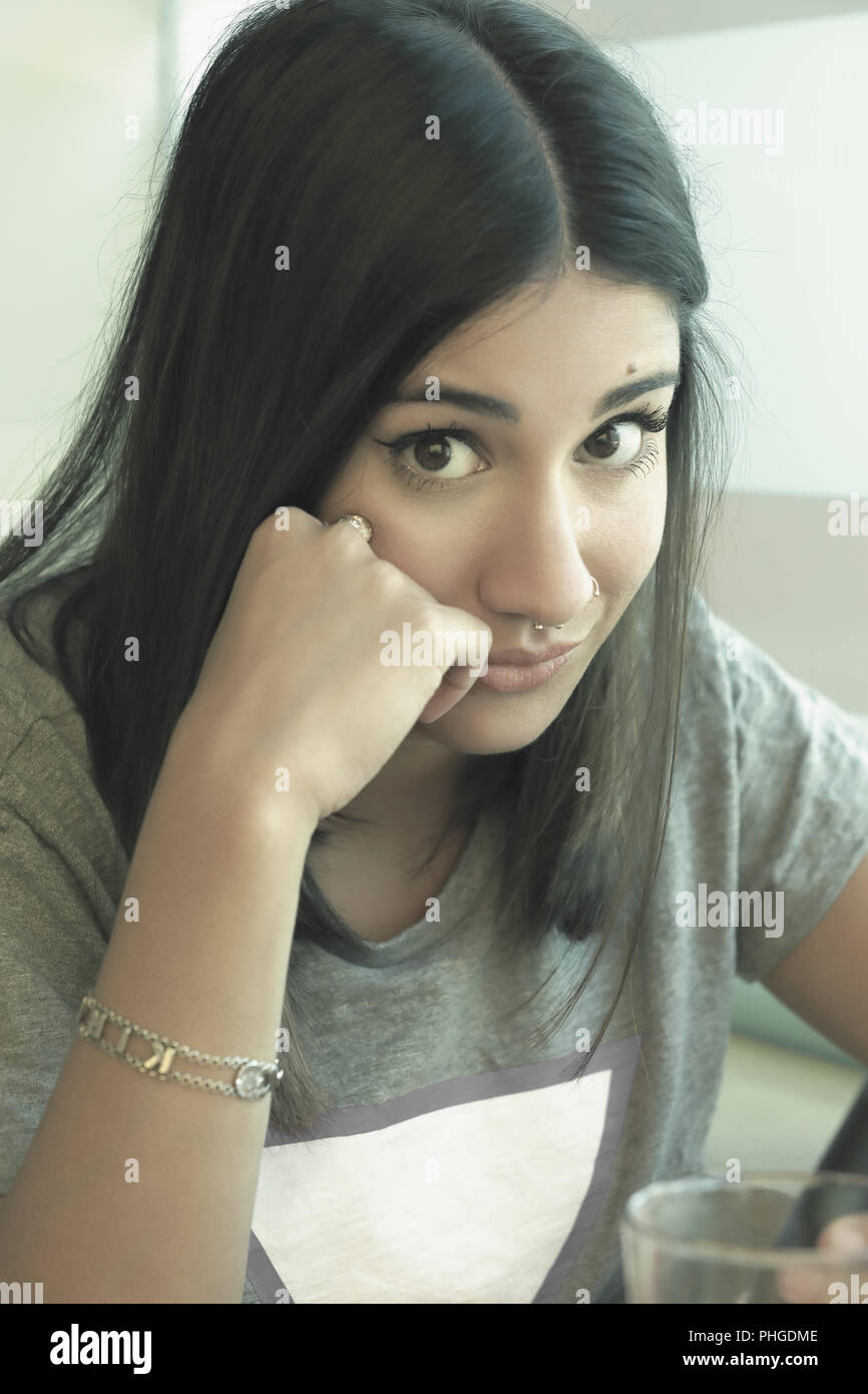 Bored cute girl looking at camera leaning her head on her hand. Stock Photo