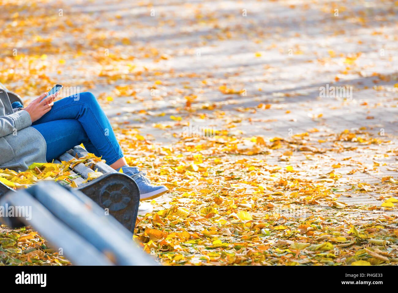 Young woman sitting on a bench in park Stock Photo - Alamy