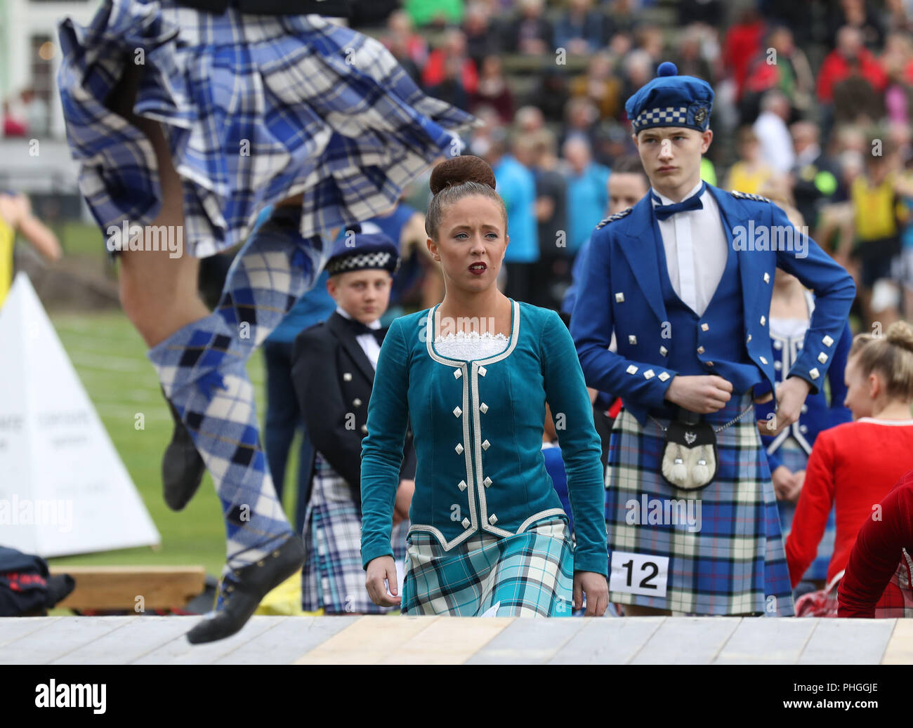 Highland dancers look on as they prepare to dance during the Braemar Royal Highland Gathering at the Princess Royal and Duke of Fife Memorial Park, Braemar. The Gathering has been run in its present form since 1832. Stock Photo