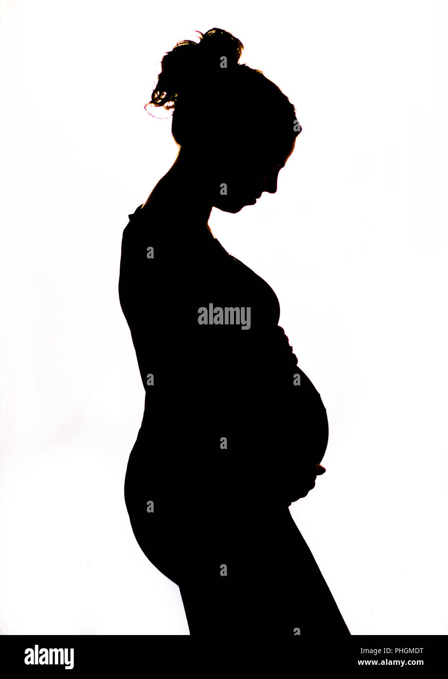 black and white silhoutte of pregnant lady cradling her bump Stock Photo