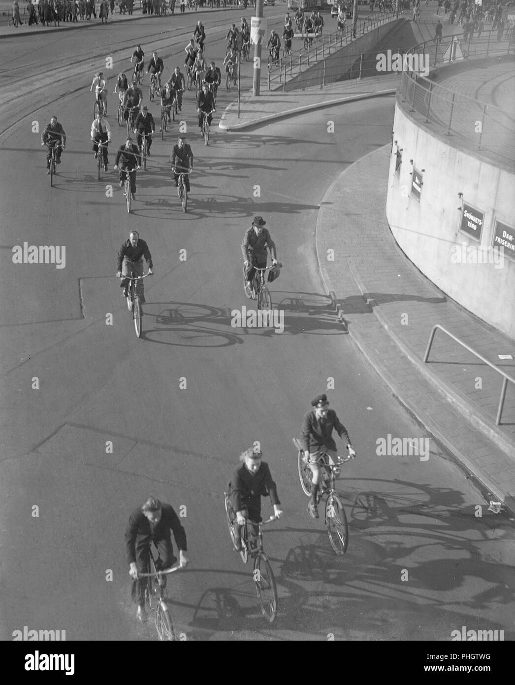 1940s cyclists. People on their bicycles are on their way through Slussen that was the traffic hub of central Stockholm, connecting the Old time with the south of Stockholm.  May 1940.  Photo Kristoffersson 129-14 Stock Photo