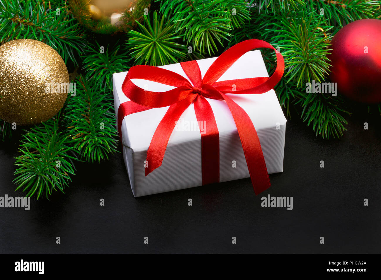 Christmas tree branch on a black background and gift box with a red ...