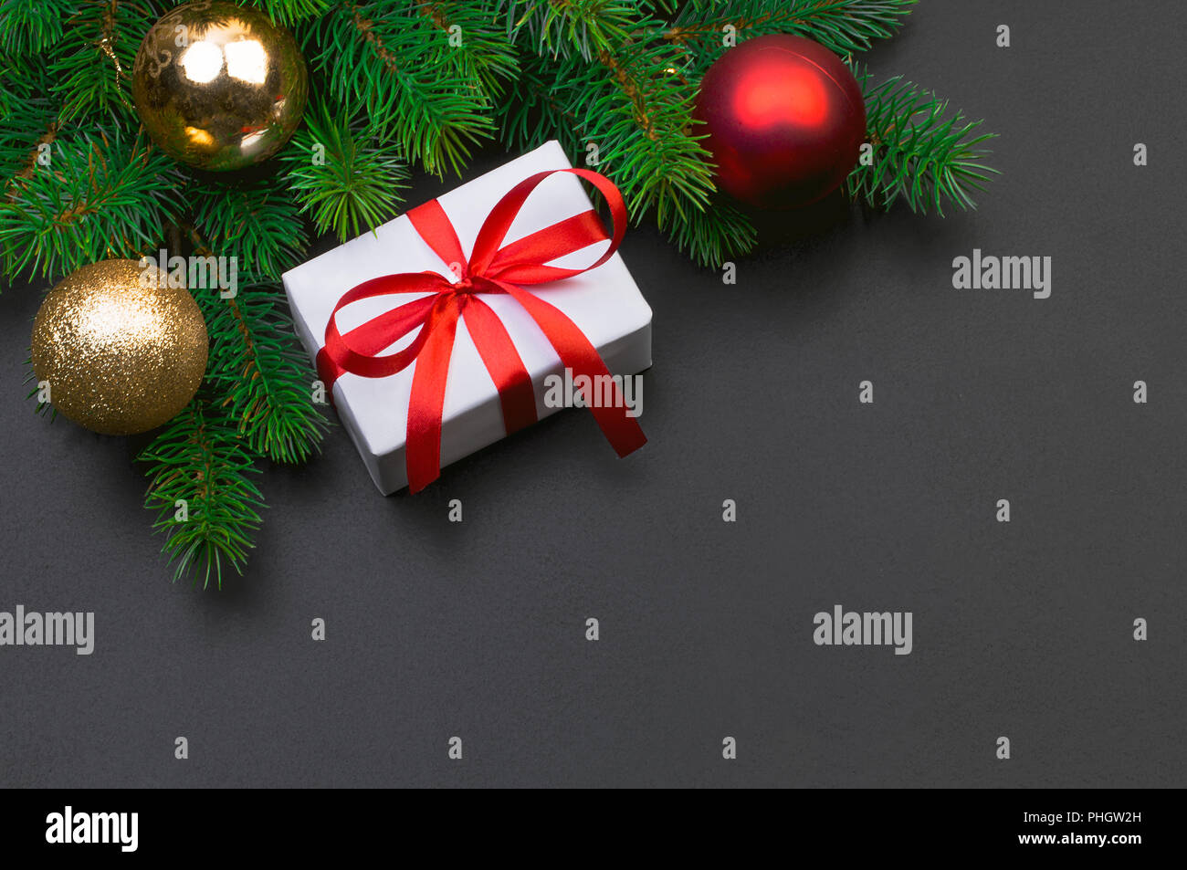 Christmas tree branch on a black background and gift box with a red ...