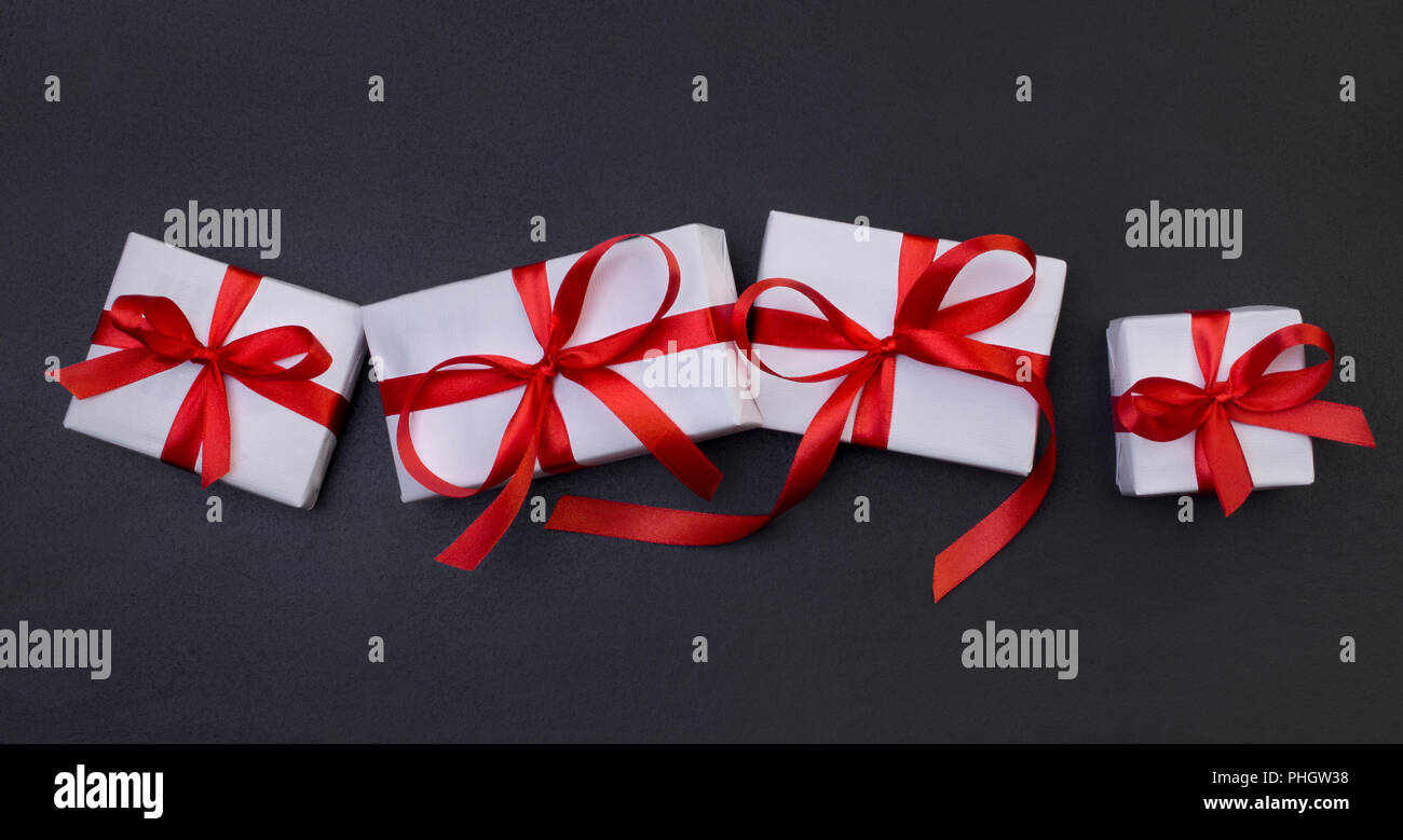 White gift boxes with a red ribbon on a black background Stock Photo
