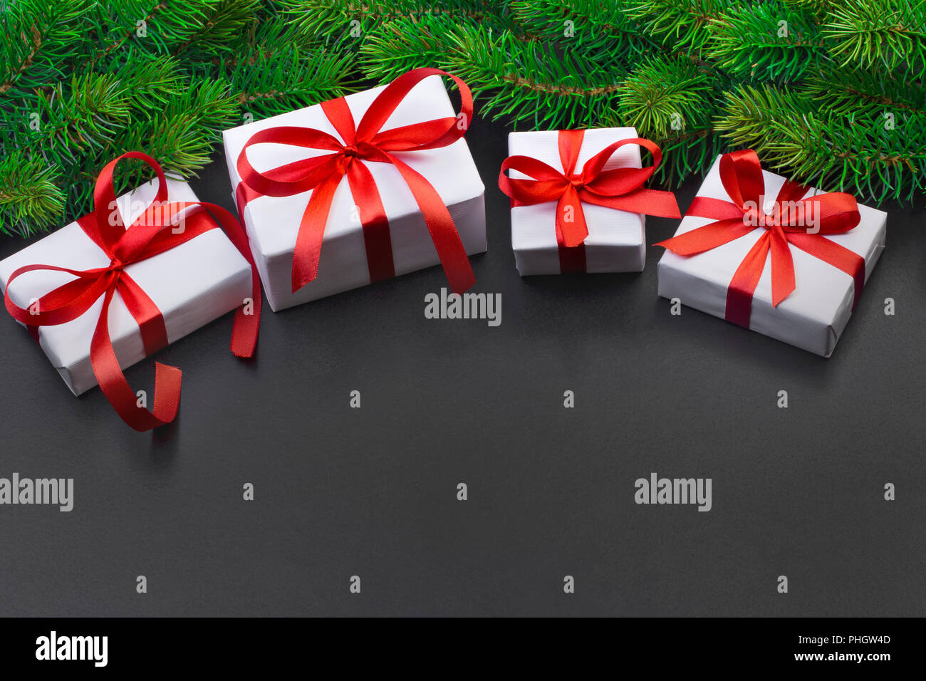 Christmas tree branch on a black background and gift box with a red ...