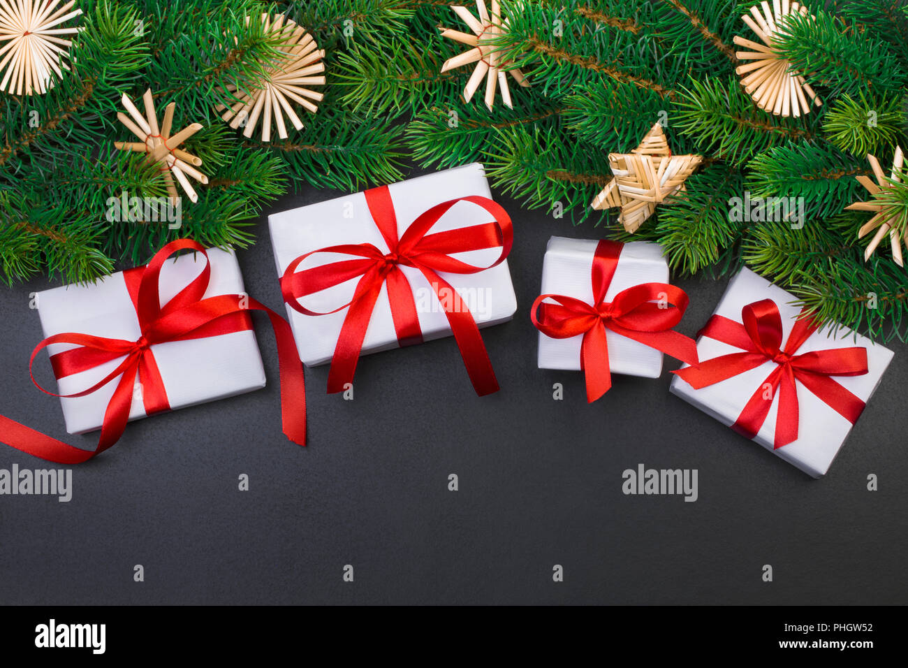 Christmas tree branch on a black background and gift box with a red ...