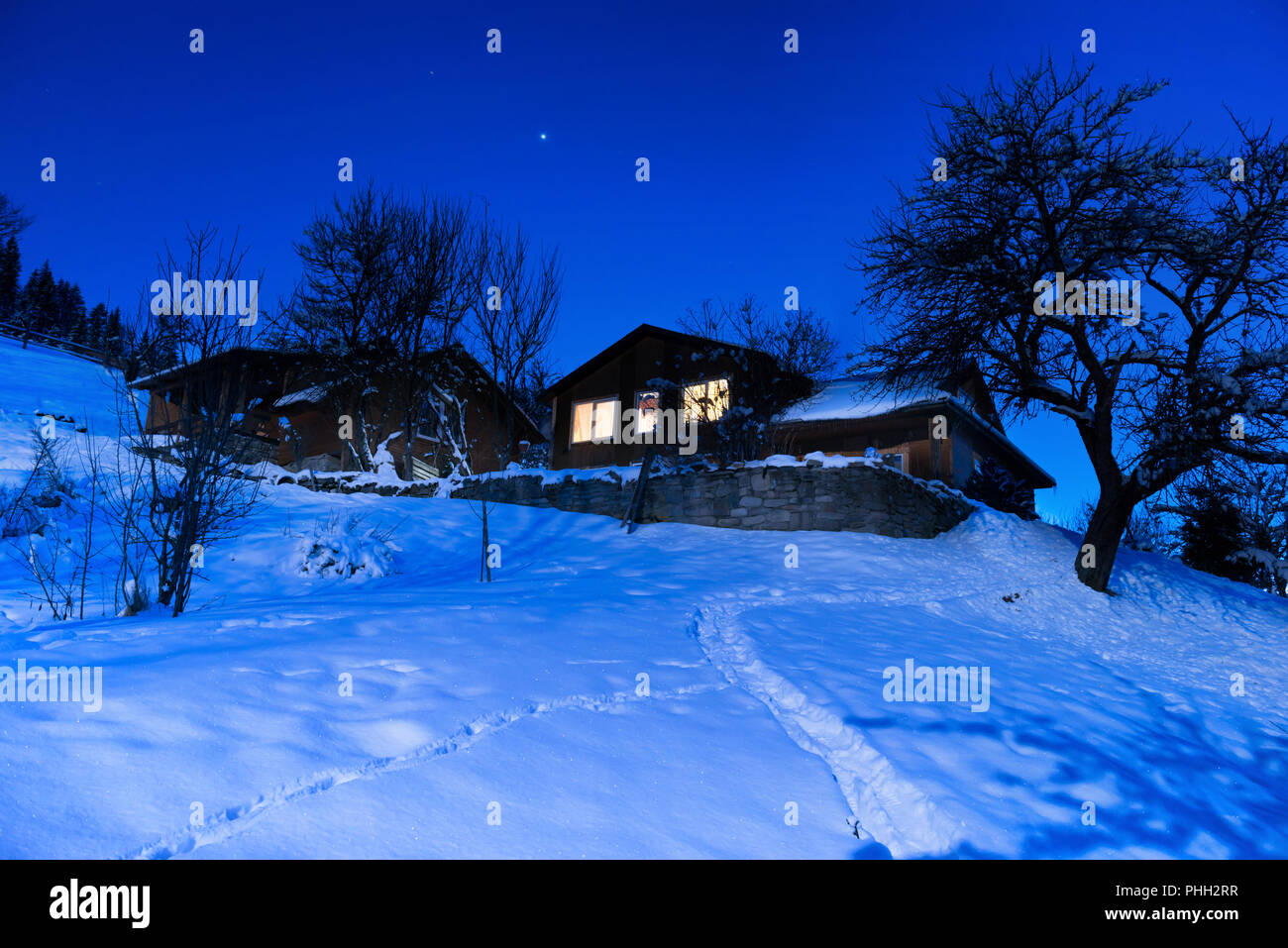 Wooden house in snow at winter night Stock Photo