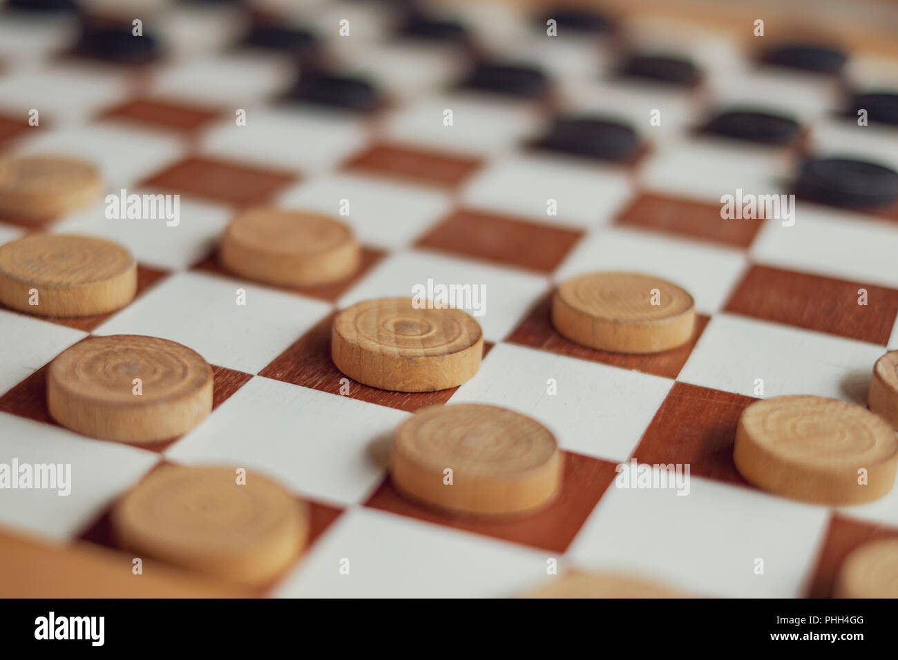 This is a wooden checkers board with black and white pawns game setup ready to play a Stock Photo
