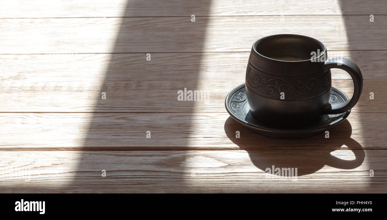 Ceramics handmade mug with milk over wooden background with morning sunrays Stock Photo