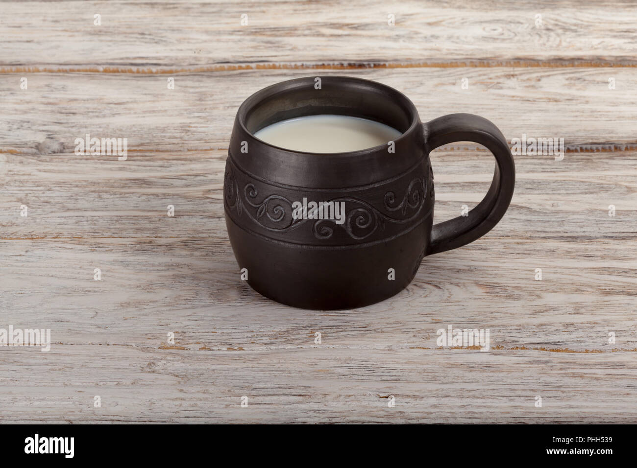 Healthy breakfast: ceramics mug with milk on wooden background Stock Photo