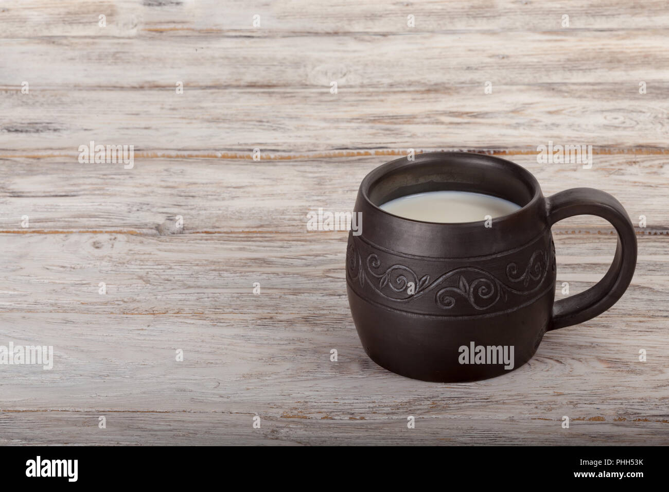 Healthy breakfast: ceramics mug with milk on wooden background Stock Photo