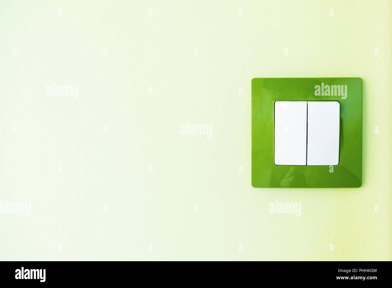 White light switch on a green wall Stock Photo