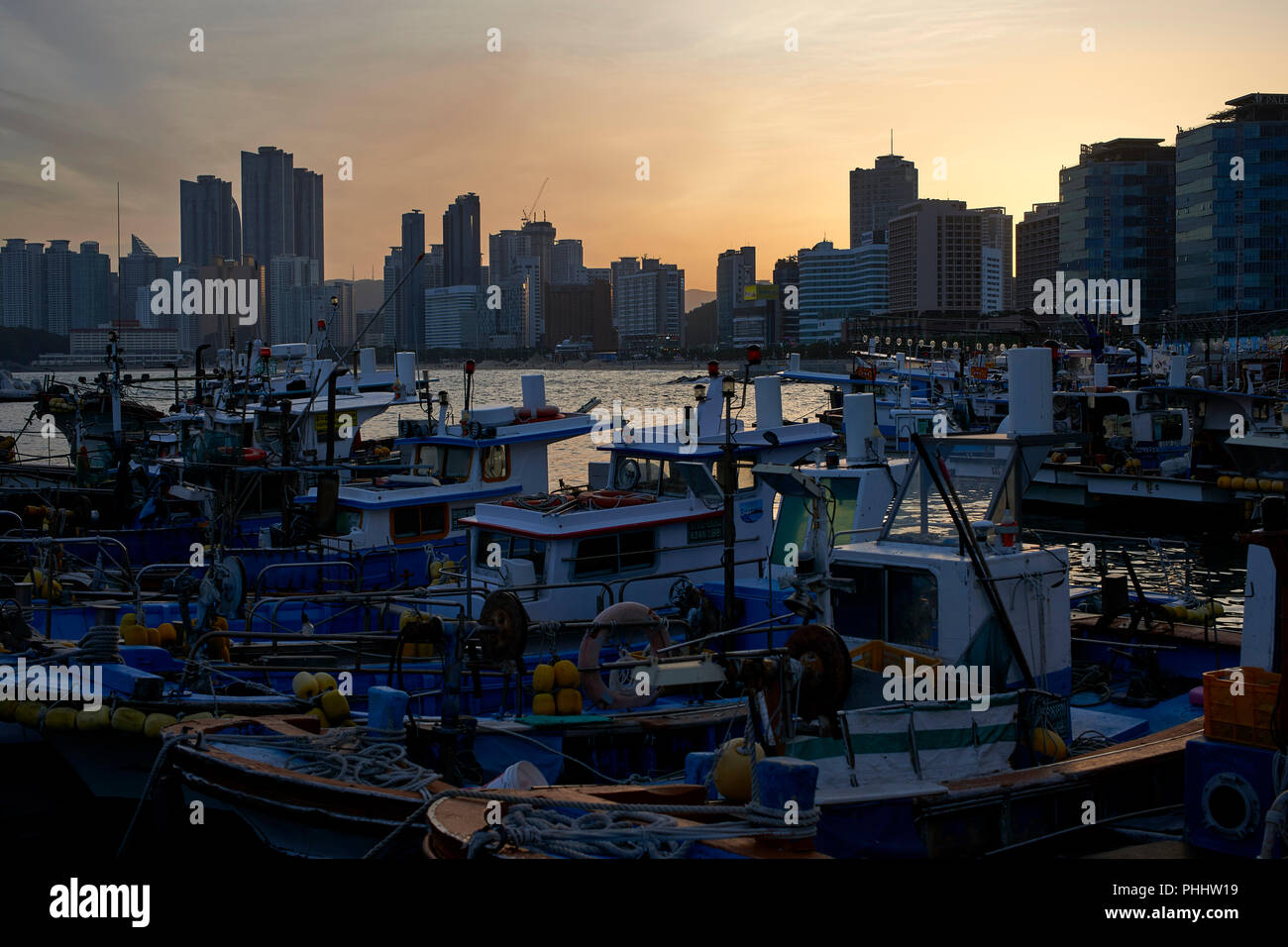 Moored fishing boats in the small harbour in Haeundae Bay, Busan Korea. Evening, sunset. Stock Photo