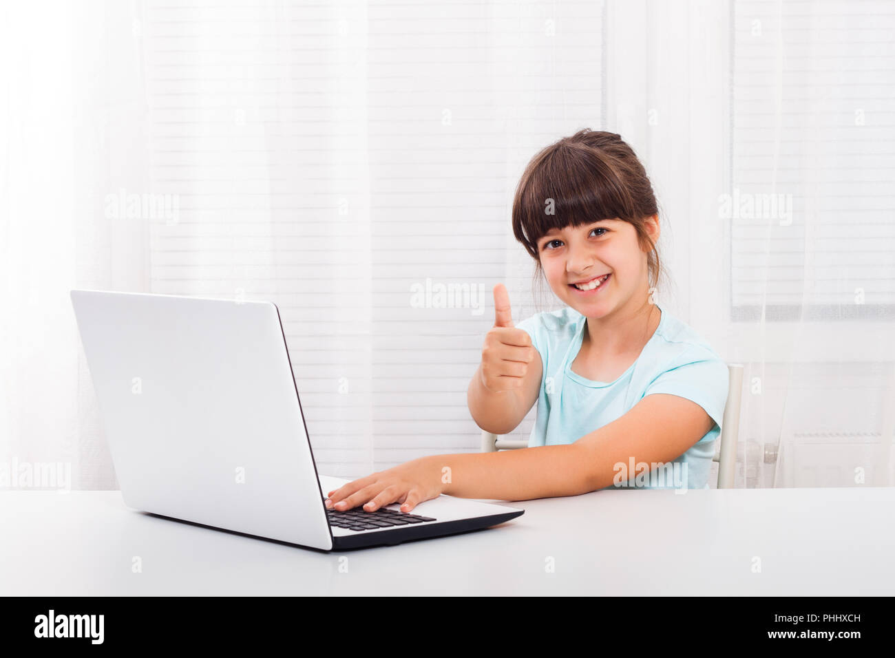 Cute little girl is using laptop.and showing thumb up Stock Photo - Alamy