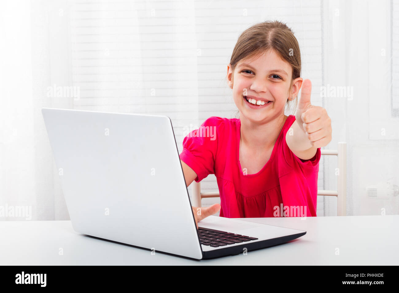 Cute little girl is using laptop.and showing thumb up Stock Photo - Alamy