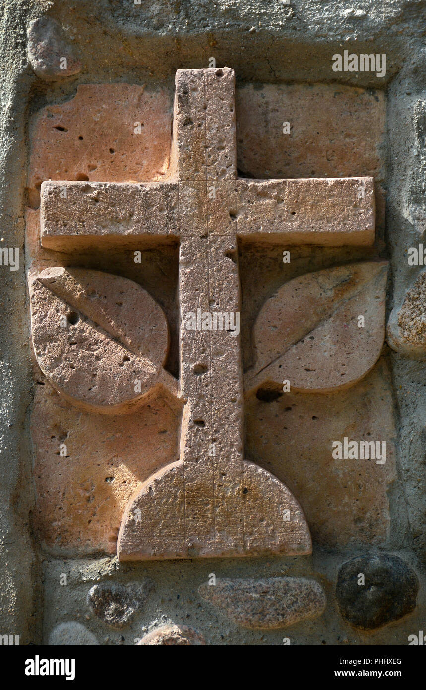 A carved stone cross embedded into the facade of a stone building in Santa Fe, New Mexico USA Stock Photo
