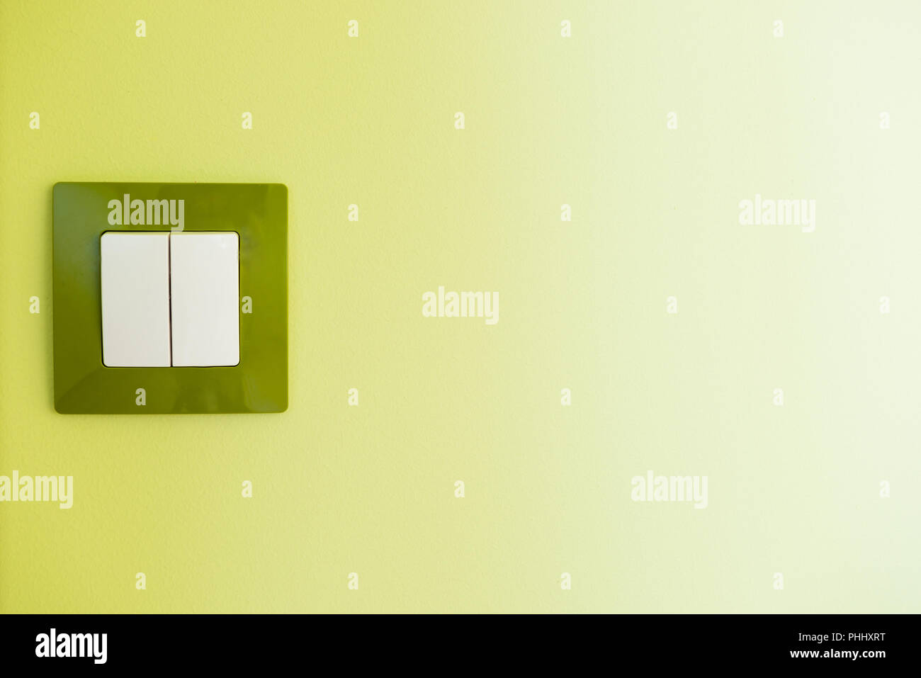 White light switch on a green wall Stock Photo