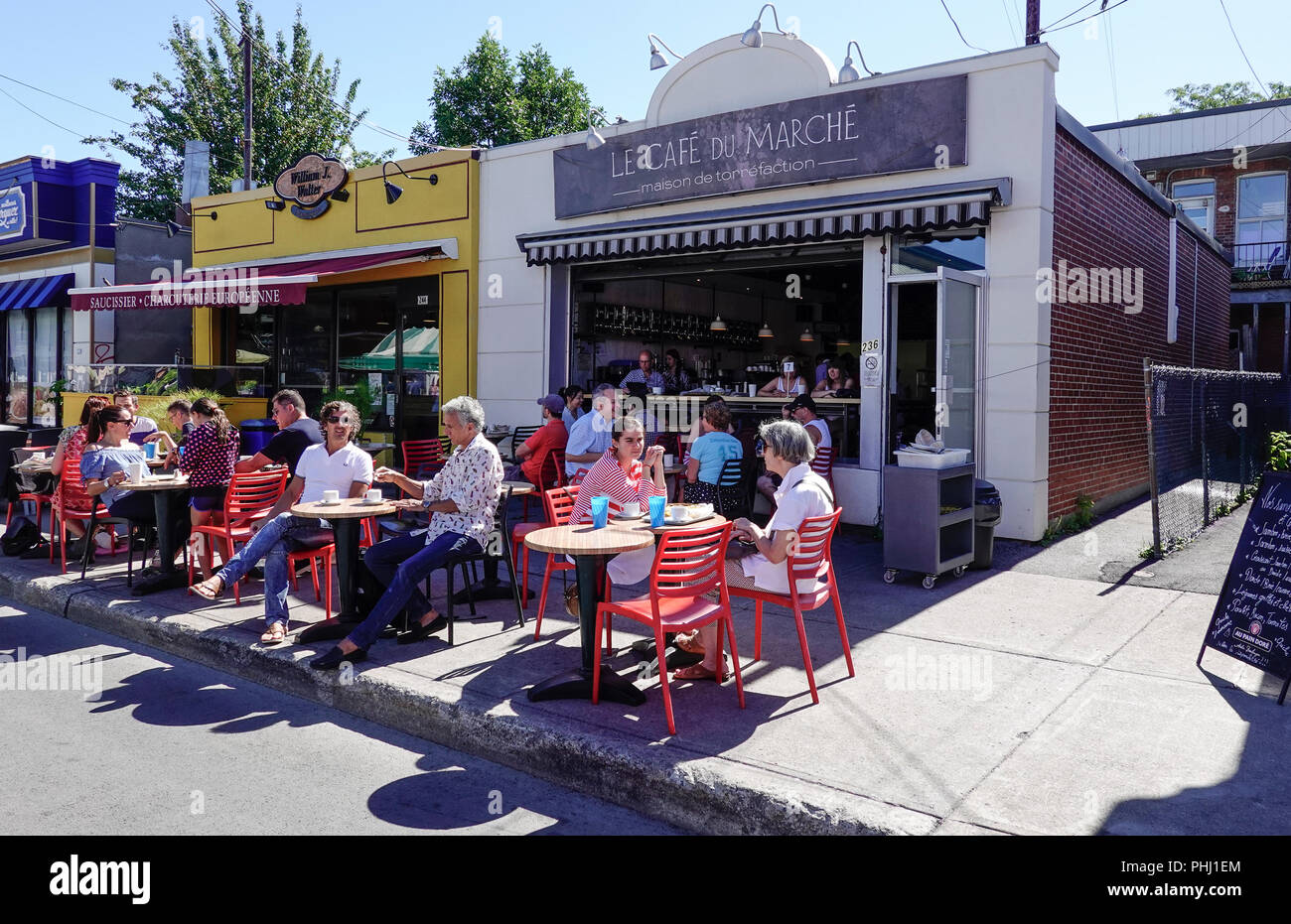 Customers enjoying a summer day dining alfresco at tables in a farmers market cafe in Montreal Stock Photo