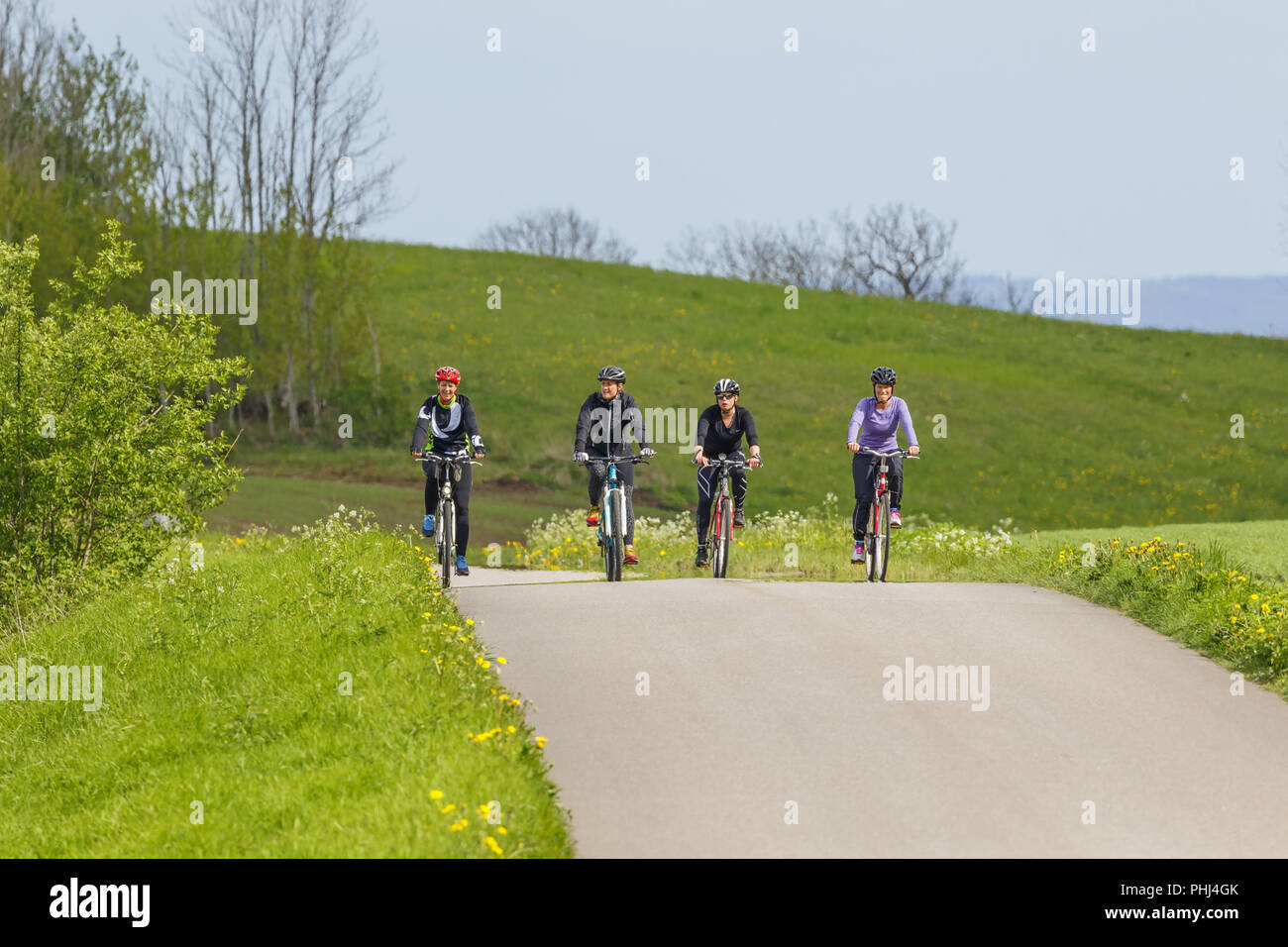 Four women riding a country road on a training trip Stock Photo