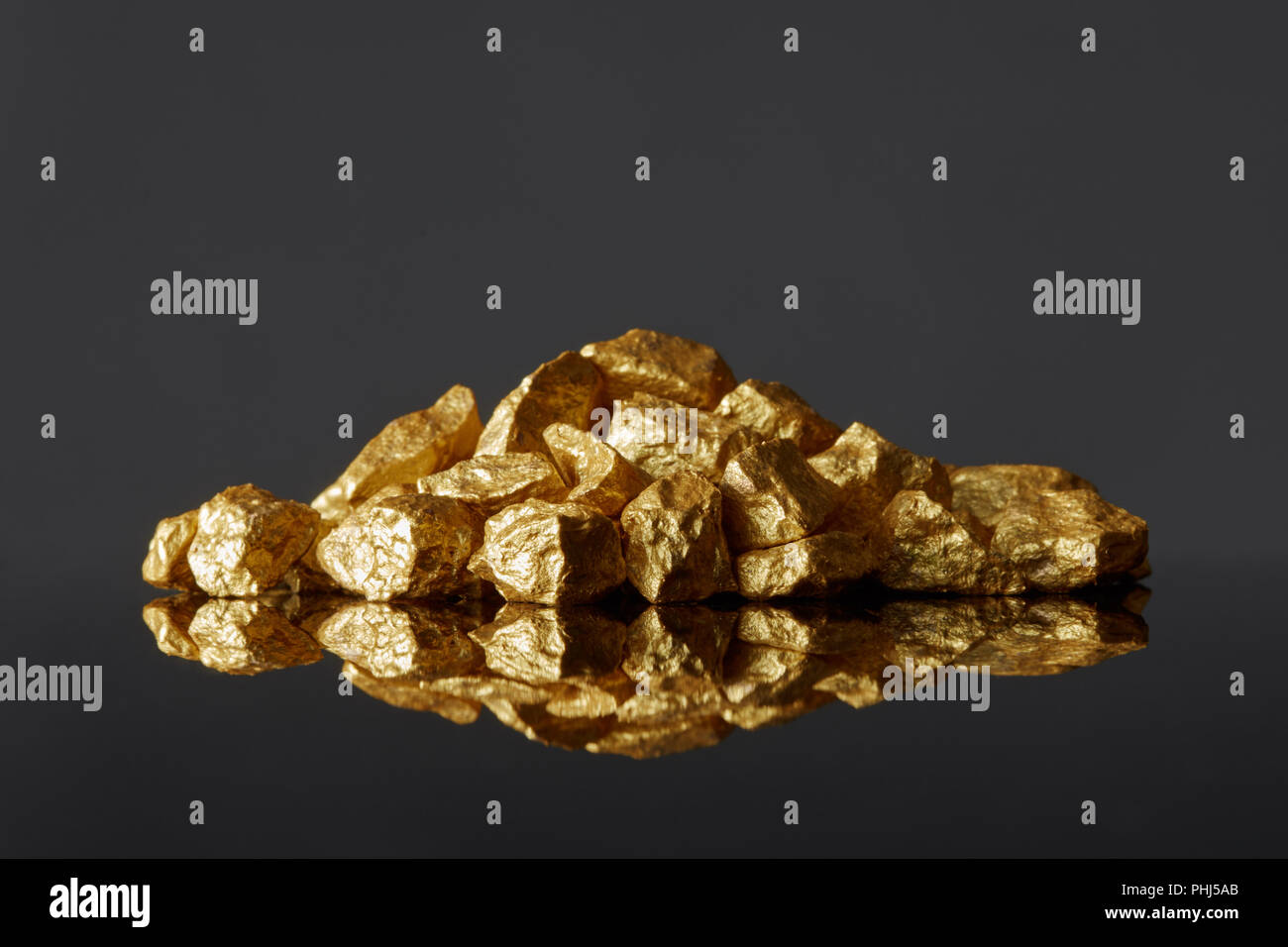 Mound of gold nuggets on a black reflective surface background Stock Photo