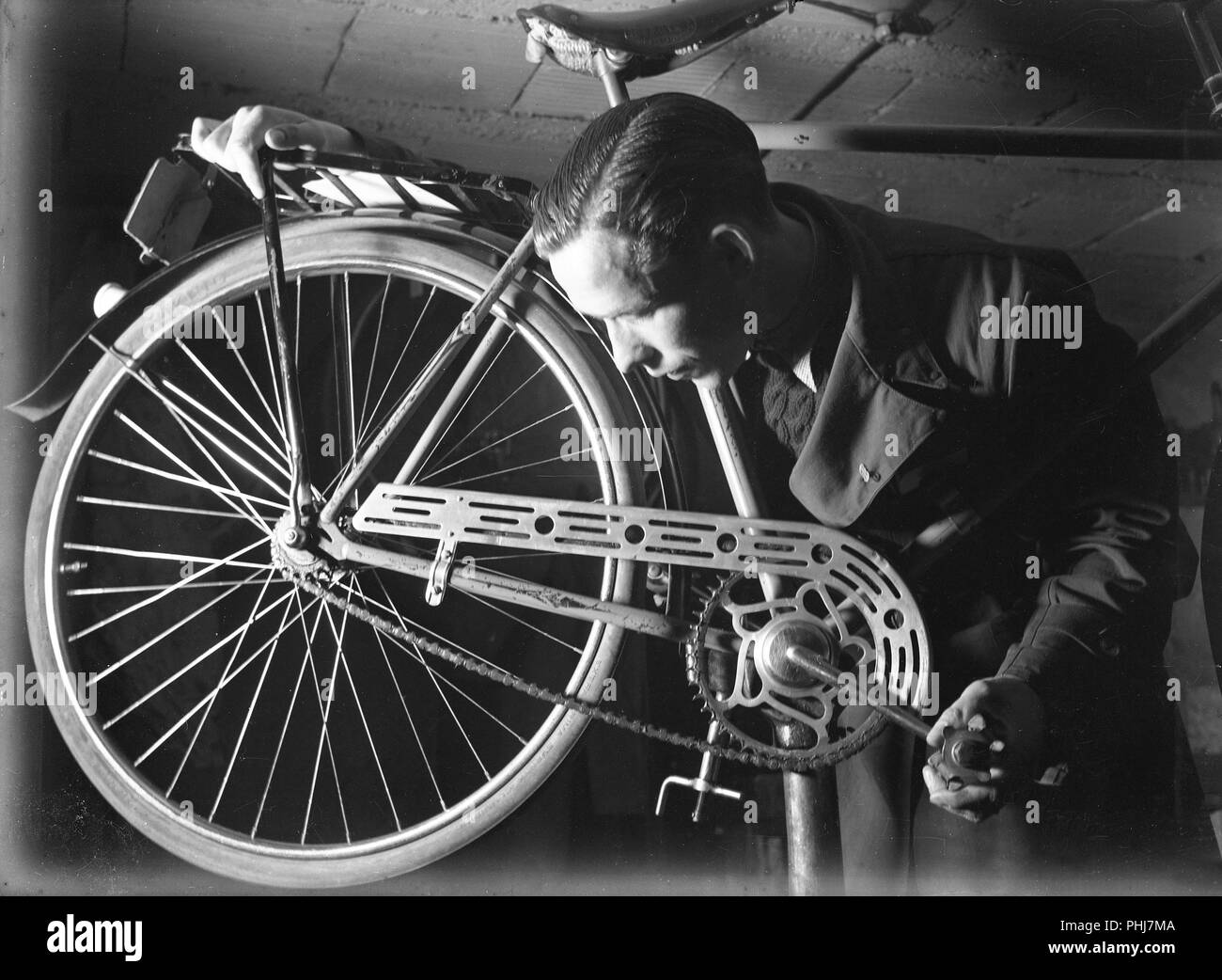 1940s man with bicycle. The Swedish athlete and olympic cyclist champion Ingvar Eriksson in his own bicycle shop where he sells and repairs bicycles. World War II has made petrol and oil expensive and rationed. Bicycles quickly became the most common means of transportation.  2 June 1940. Photo Kristoffersson 150-8 Stock Photo