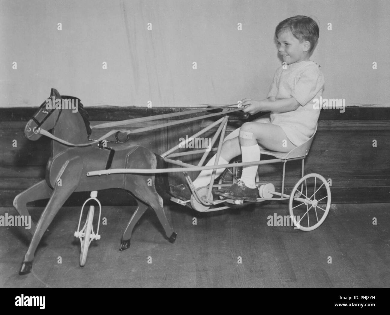 19s0s bicycle toy. A boy is trying this years favorite childrens toy, a pedal car as a horse and carrriage. Sweden 1944 Stock Photo