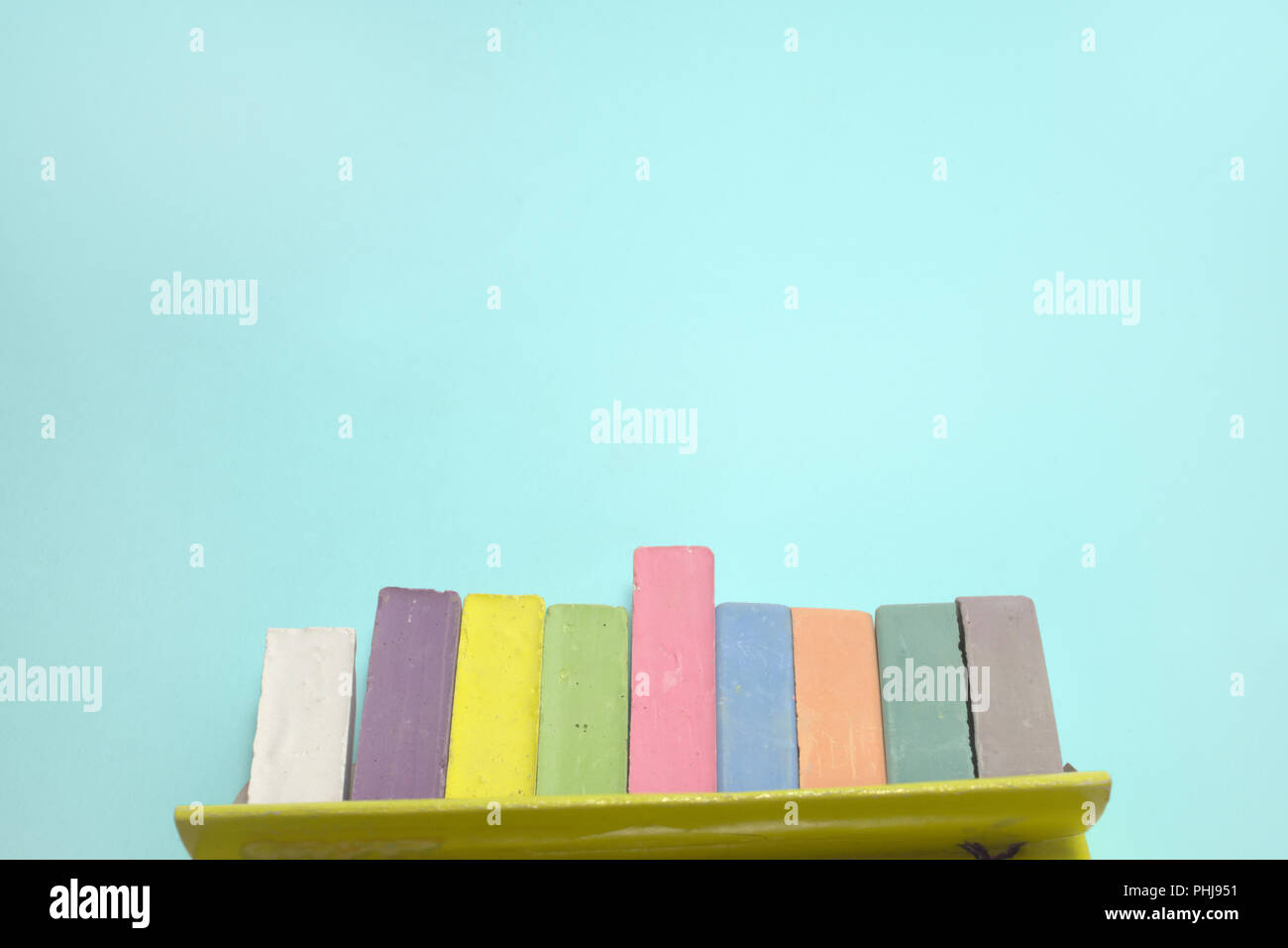 chalks for drawing colored set take out from open cardboard box. children creativity pieces on cyan background with clipping path Stock Photo