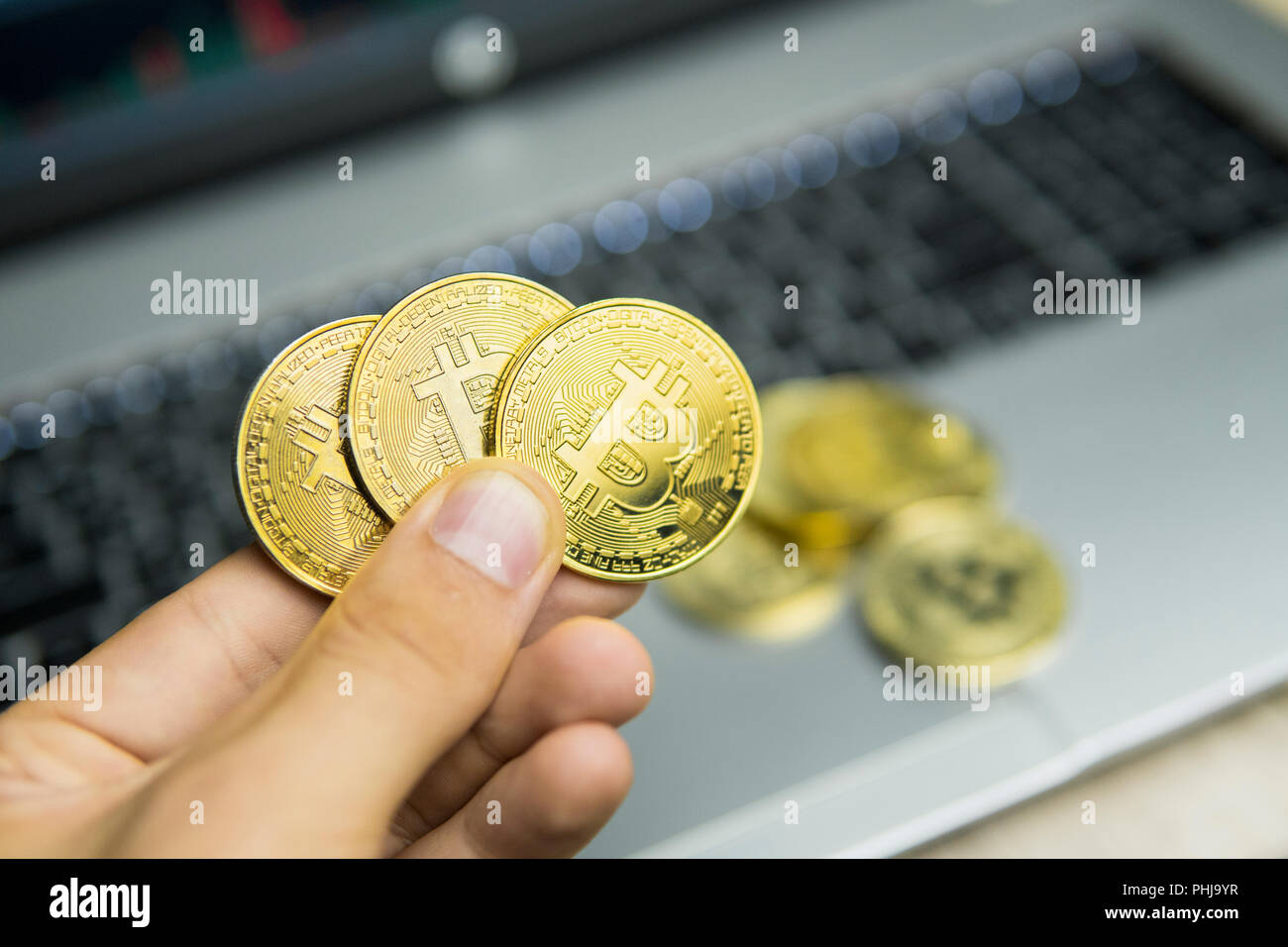 Male businessman hand holding tree bitcoin on a background of laptop  keyboard and pile of golden coins. Virtual money and Financial growth  concept. Trading Mining of bitcoins Stock Photo - Alamy