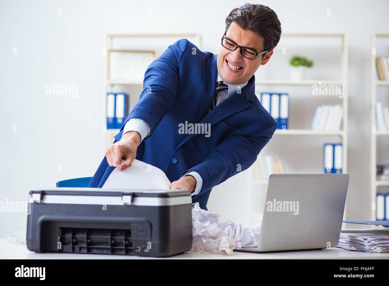 Businessman angry at copying machine jamming papers Stock Photo Alamy