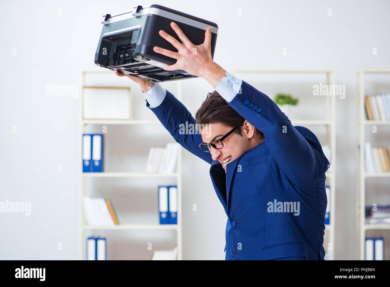 Businessman angry at copying machine jamming papers Stock Photo - Alamy