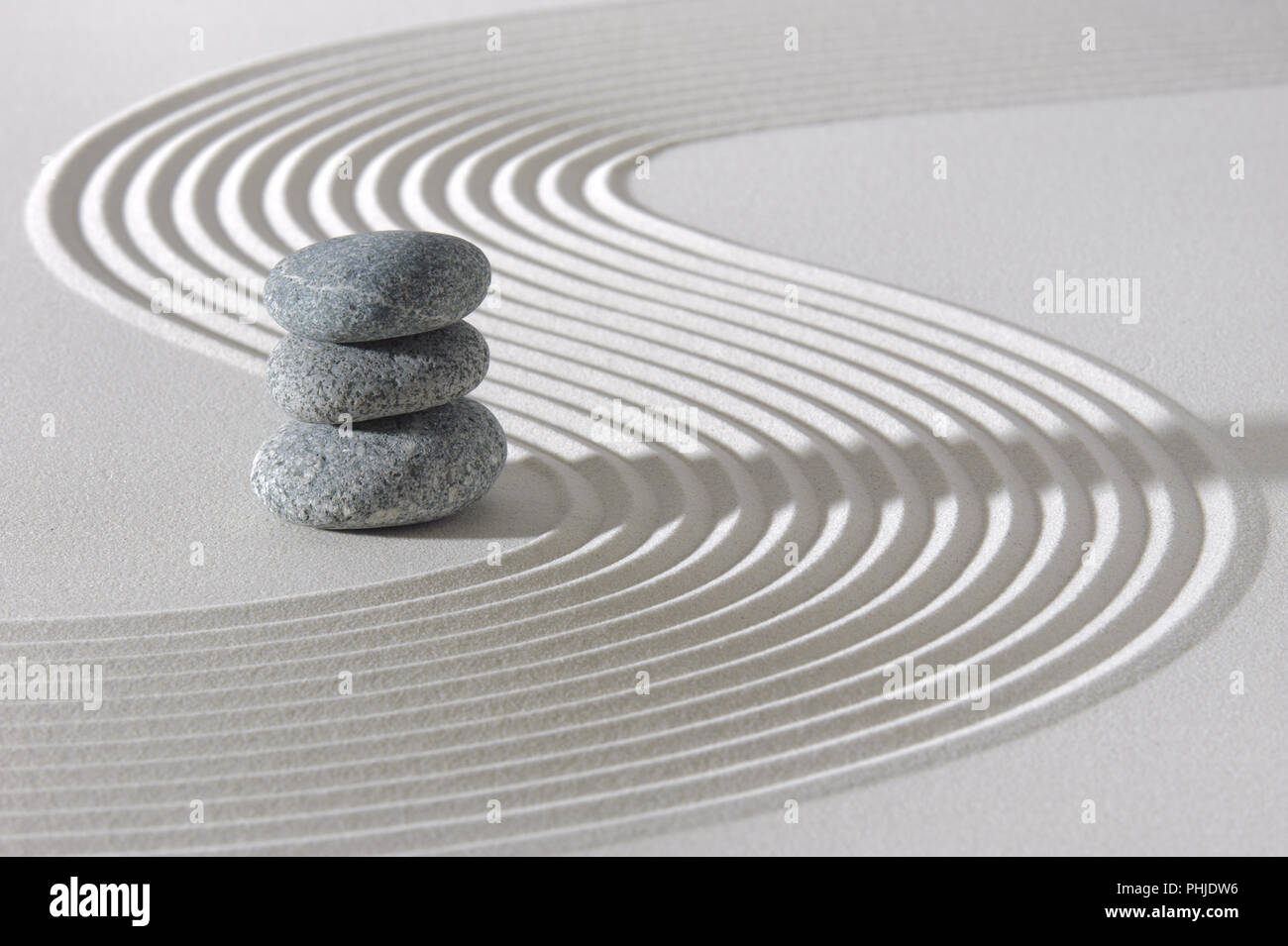 Japanese zen garden with stacked stones in white sand Stock Photo