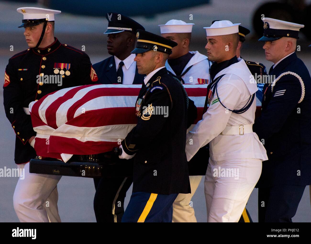 A U.S. Military Joint Service honor guard carries the flag-draped casket of Sen. John S. McCain III after arrival from Arizona August 30, 2018 at Joint Base Andrews, Maryland. The former senator’s remains are en route to lie in state in the U.S. Capitol Rotunda before burial at the U.S. Naval Academy. Stock Photo