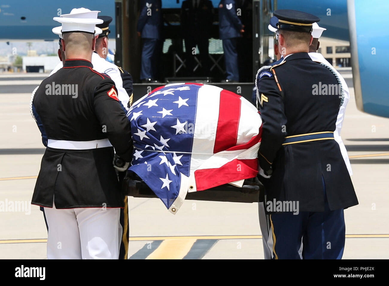 The flag draped casket of Sen. John McCain is carried by a Joint Service honor guard for transport to Washington, DC August 29, 2018 in Phoenix, Arizona. The former senator’s remains will lie in state in the U.S. Capitol Rotunda before burial at the U.S. Naval Academy. Stock Photo