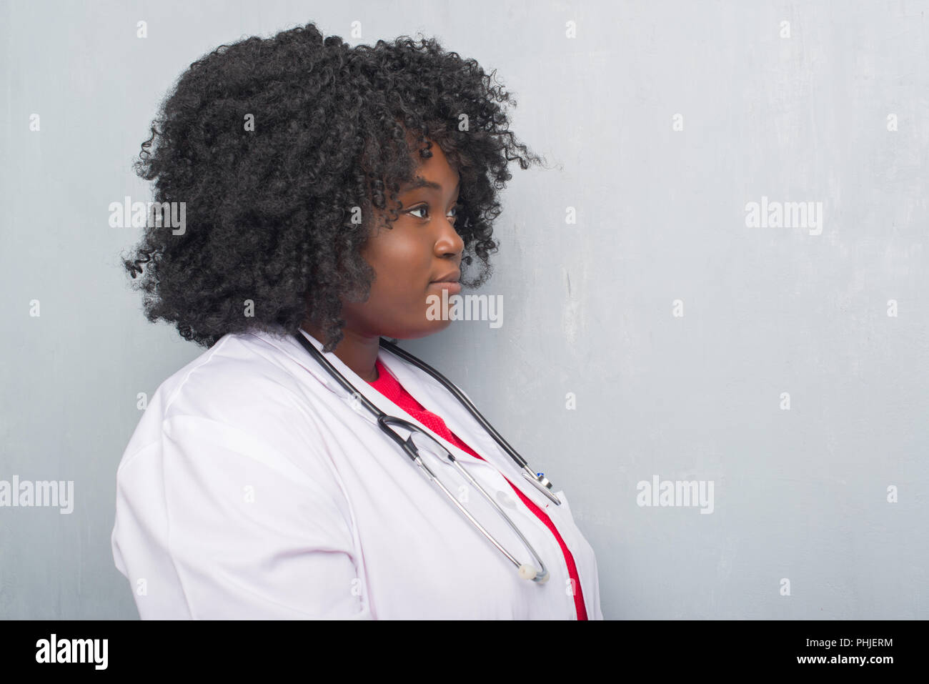 Young African American Doctor Woman Over Grey Grunge Wall Looking